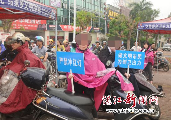 闯红灯、电动车逆向行驶者举牌宣传交通文明。