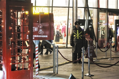 昨晚8时，在三里屯的一家商铺前，一名保安站在圣诞节装饰前站岗。